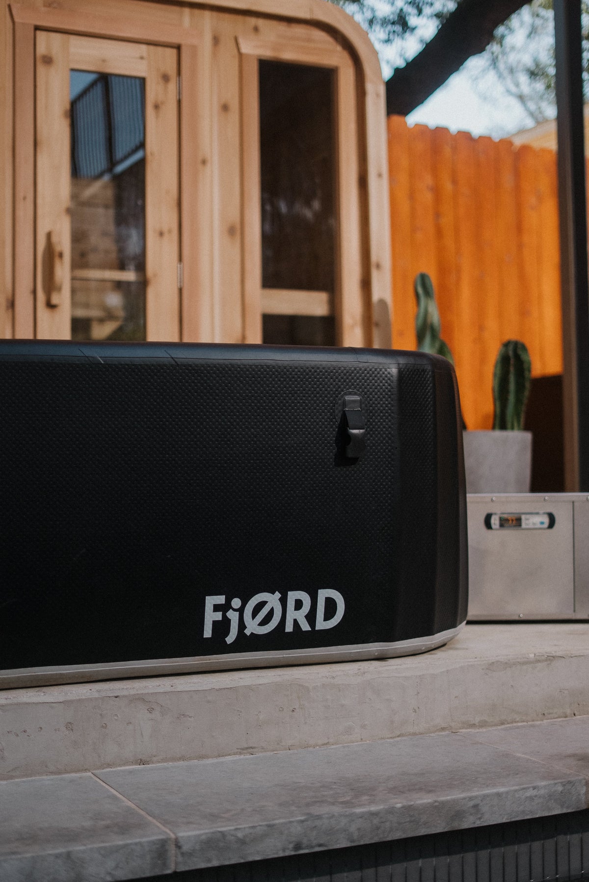 FjØRD Sport cold plunge set up on a patio beside a cedar sauna
