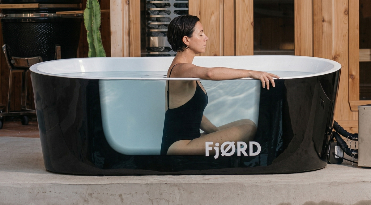 Woman sitting in a FjØRD cold plunge tub practising slow breathwork outdoors